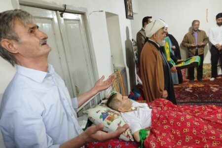پرچم متبرک شده حرم مطهر رضوی بر بالین پاکبان بیمار گوگانی